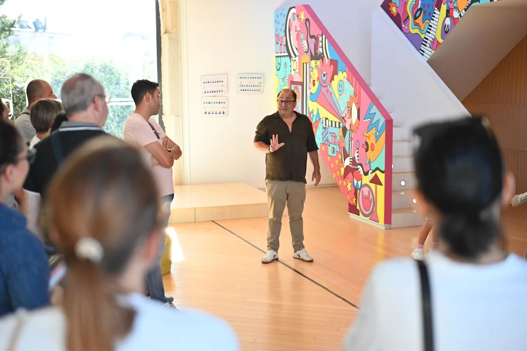 Explicación ao público no vestíbulo do Conservatorio de Verín, diante do mural de cores da escaleira.