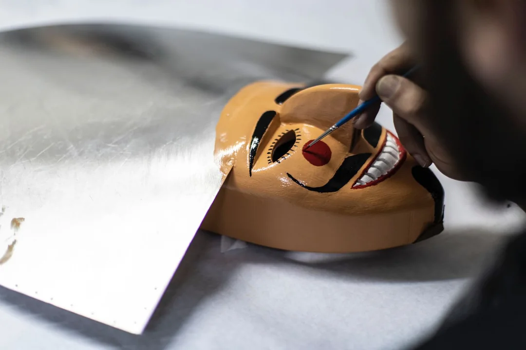 Pintado a man dunha careta de cigarrón, coa súa característica cor carne, os trazos negros e o sorriso branco e vermello.