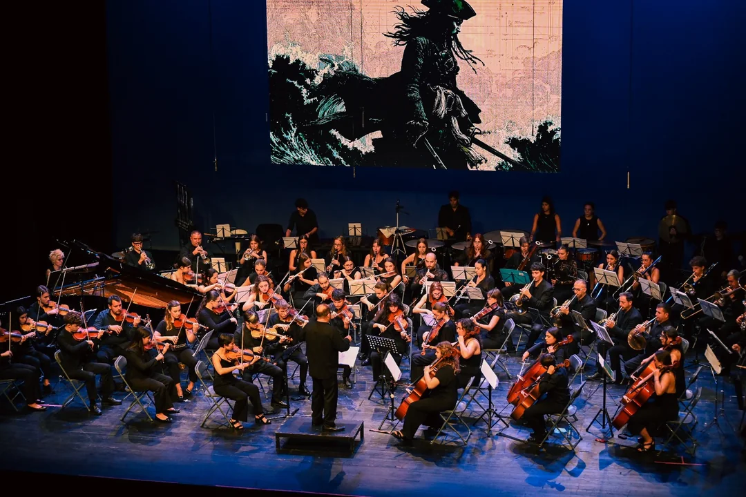 A Sinfónica Cinematográfica do OUFF durante un concerto, coa orquestra ao completo no escenario e unha proxección cinematográfica ao fondo.